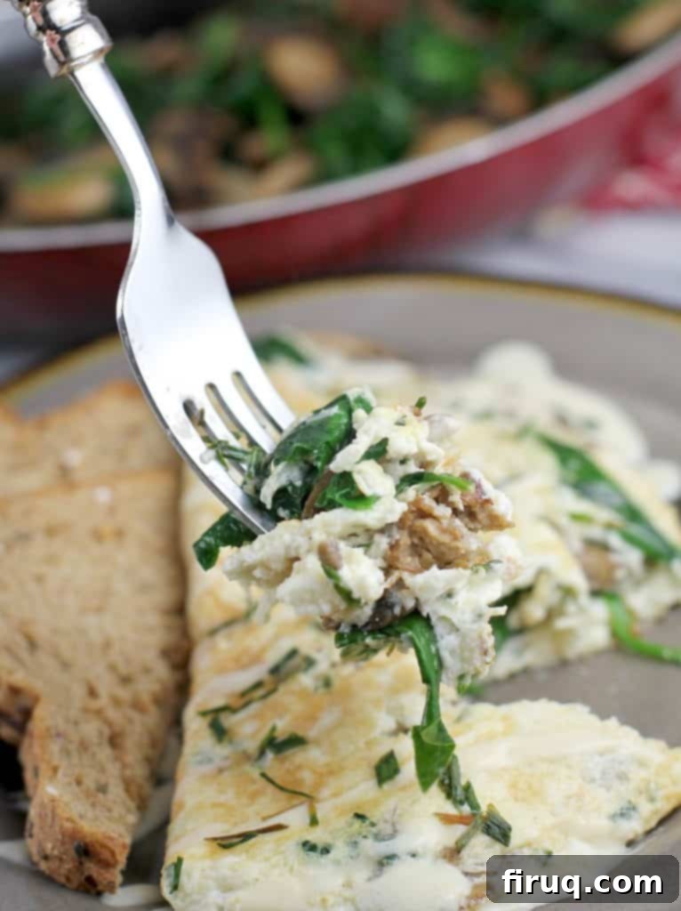 Plant-Powered Omelet with Savory Sausage, Spinach, and Mushrooms 11 finished omelet with a fork holding up a biteful