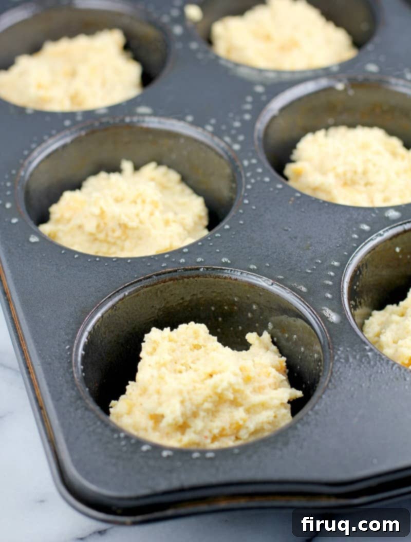 Guilt-Free Cheddar Bay Biscuits 9 Biscuit batter carefully scooped into a muffin tin, ready for baking