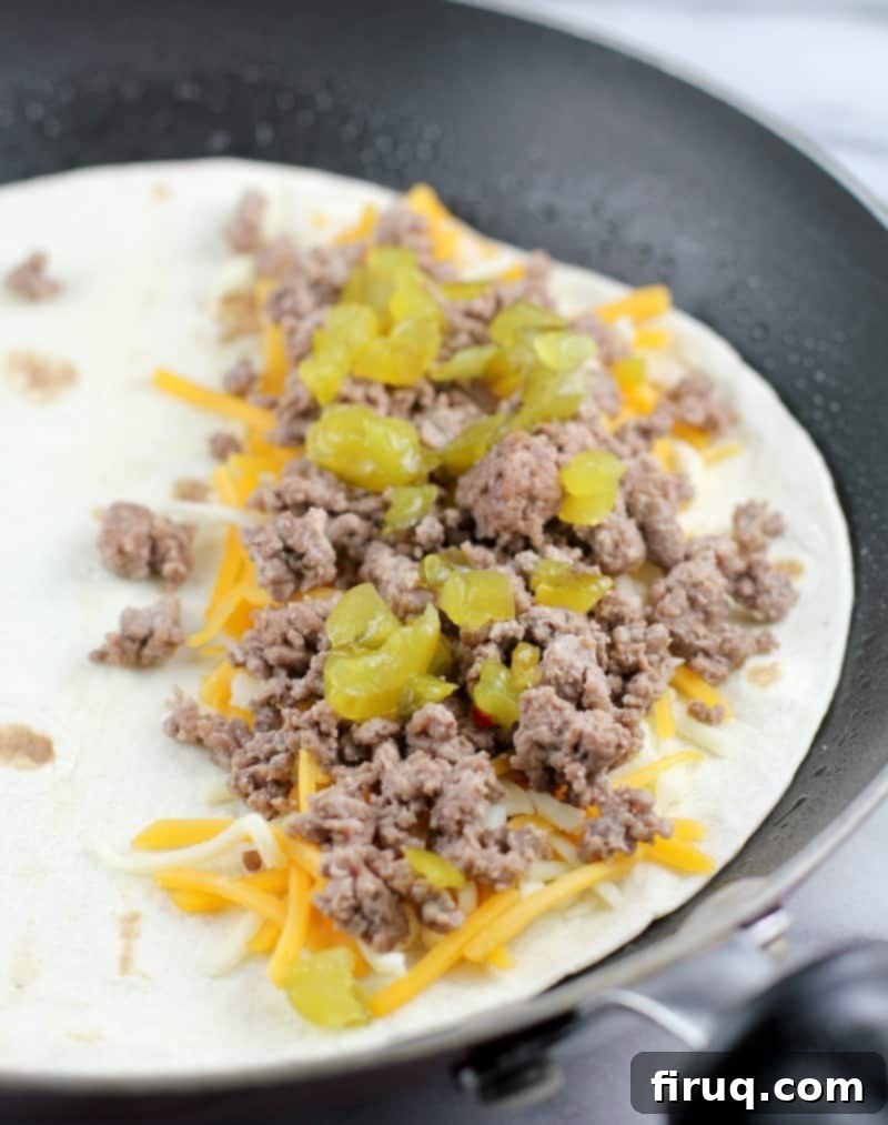 Loaded Burger Fry Quesadilla 8 open quesadilla cooking in the pan showing cheese, meat, and pickle