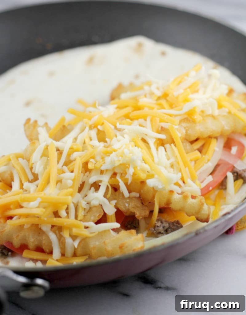 Loaded Burger Fry Quesadilla 9 all the toppings layered in an open tortilla cooking in the pan