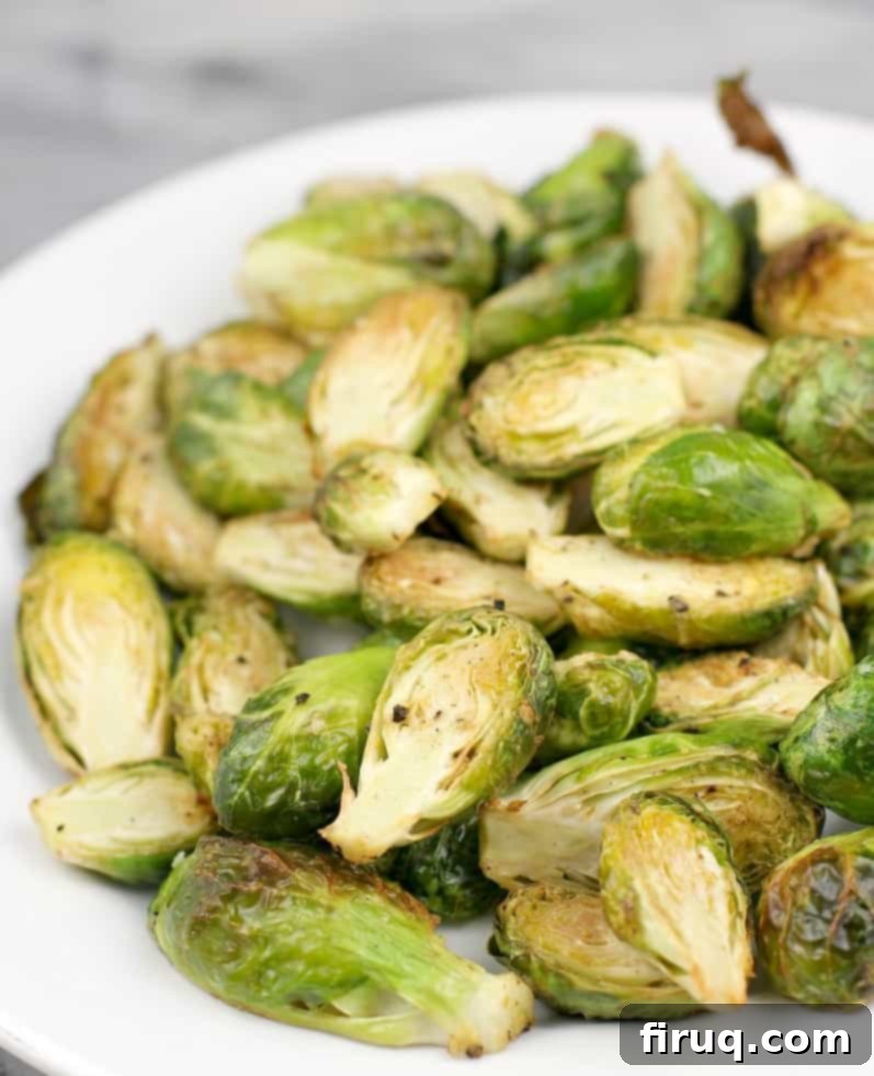 Crispy Air-Fried Brussels Sprouts 6 Cooked air-fried Brussels sprouts piled on a plate, before the addition of Parmesan cheese, showing their golden brown and crispy texture.