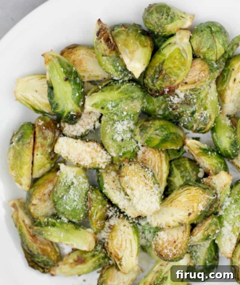 Crispy Air-Fried Brussels Sprouts 8 Top-down view of the beautifully cooked air-fried Brussels sprouts with Parmesan and a side of lemon aioli, served on a white plate.