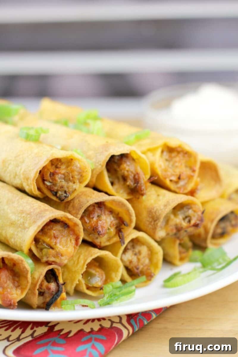 Crispy Air Fryer Pulled Pork Taquitos 2 side view of taquitos on a white dish, garnished with green onions and sour cream