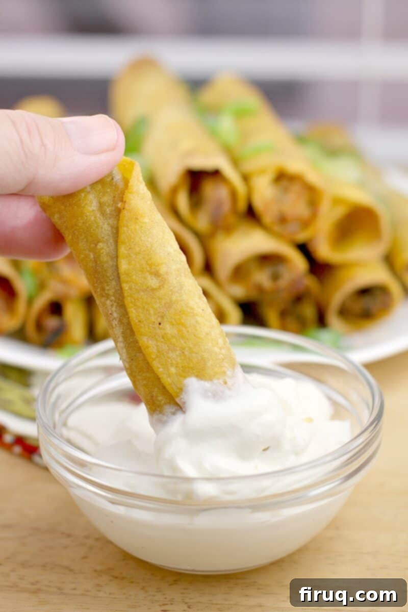 Crispy Air Fryer Pulled Pork Taquitos 3 hand dipping taquito in sour cream