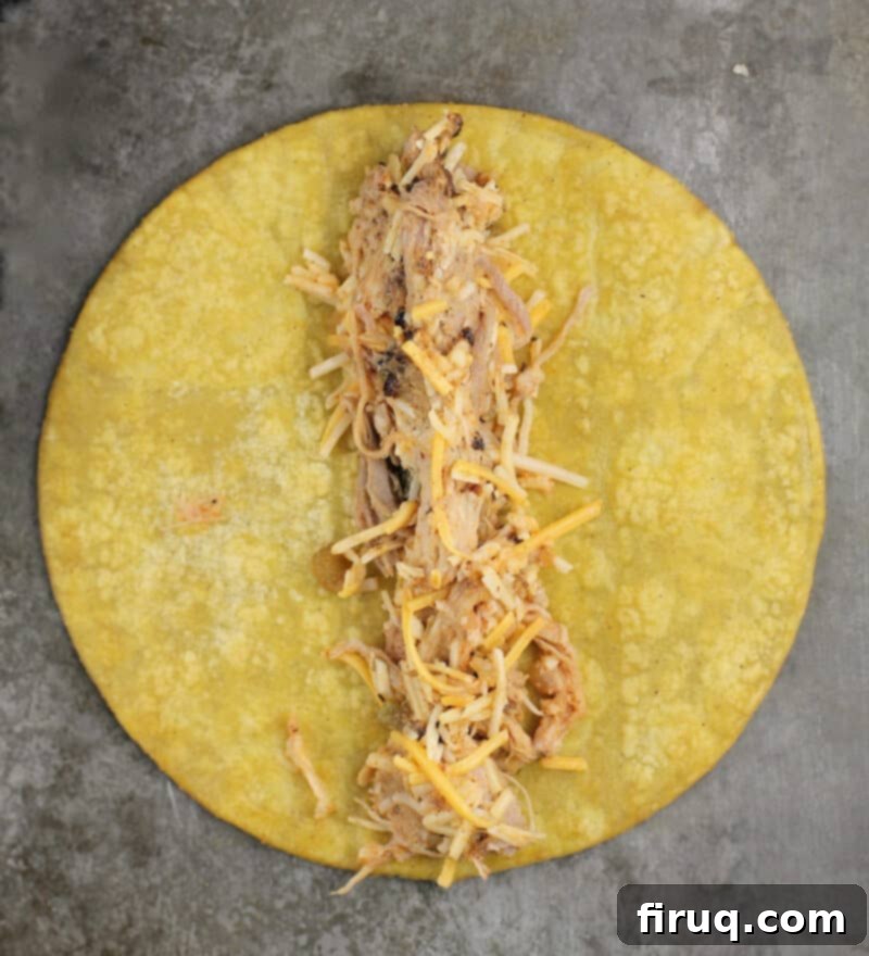 Crispy Air Fryer Pulled Pork Taquitos 7 pulled pork filling down the center of a corn tortilla, ready to be rolled
