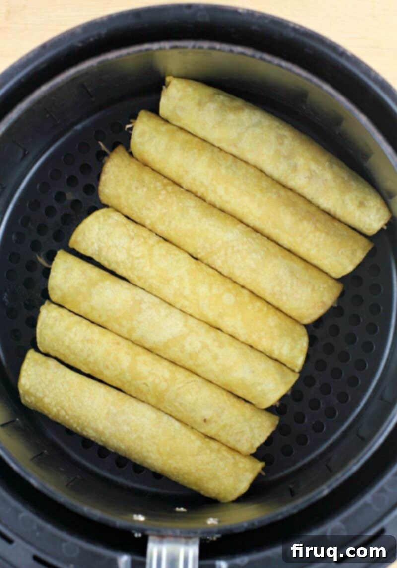 Crispy Air Fryer Pulled Pork Taquitos 8 rolled corn tortillas neatly arranged in an air fryer basket