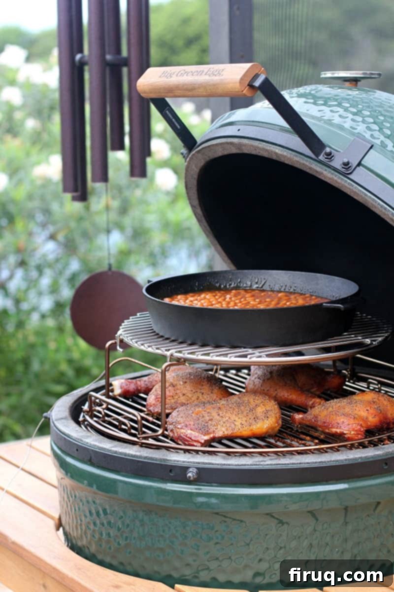 Sweet & Smoky Maple Bourbon Chicken 6 view in a Big Green Egg with chicken cooked on a low grate and a cast iron pan of beans on an upper grate
