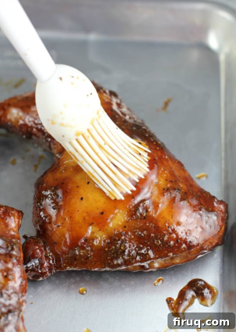 Sweet & Smoky Maple Bourbon Chicken 7 maple bourbon glaze being mopped on a piece of cooked chicken