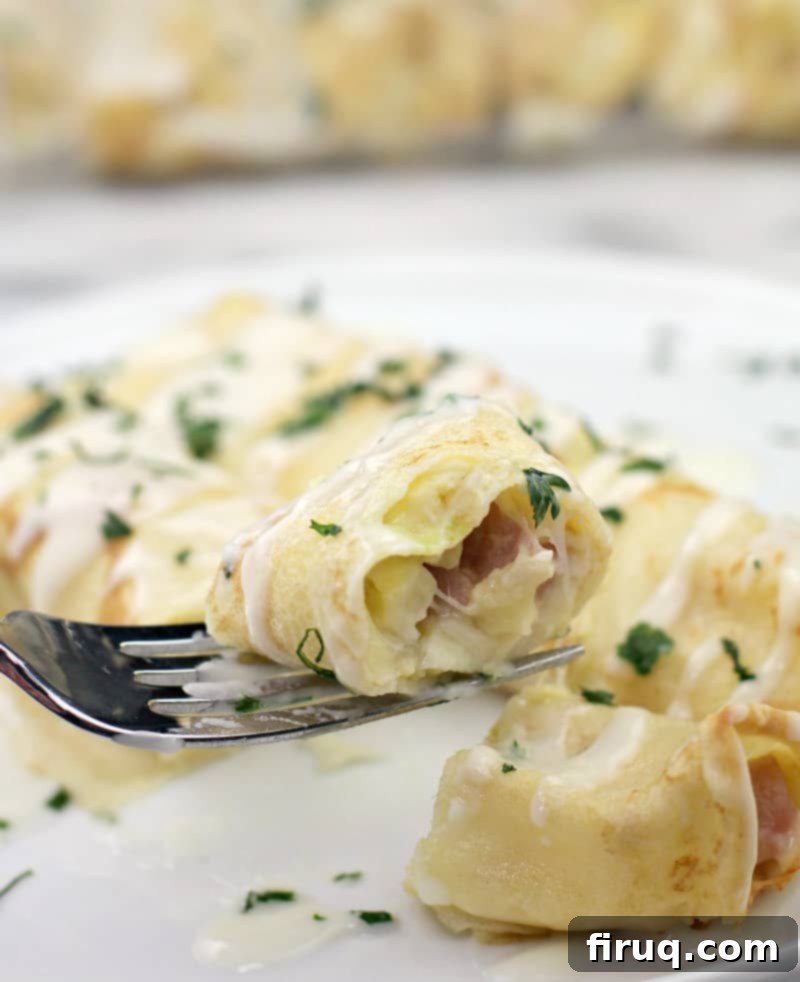 Creamy Béchamel Ham and Cheese Breakfast Crepes 11 fork holding a bite of breakfast crepe