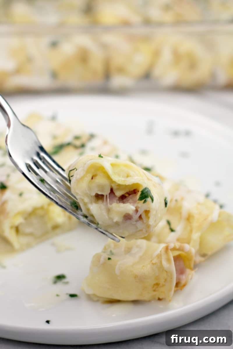 Creamy Béchamel Ham and Cheese Breakfast Crepes 3 fork holding a piece of ham and cheese crepe