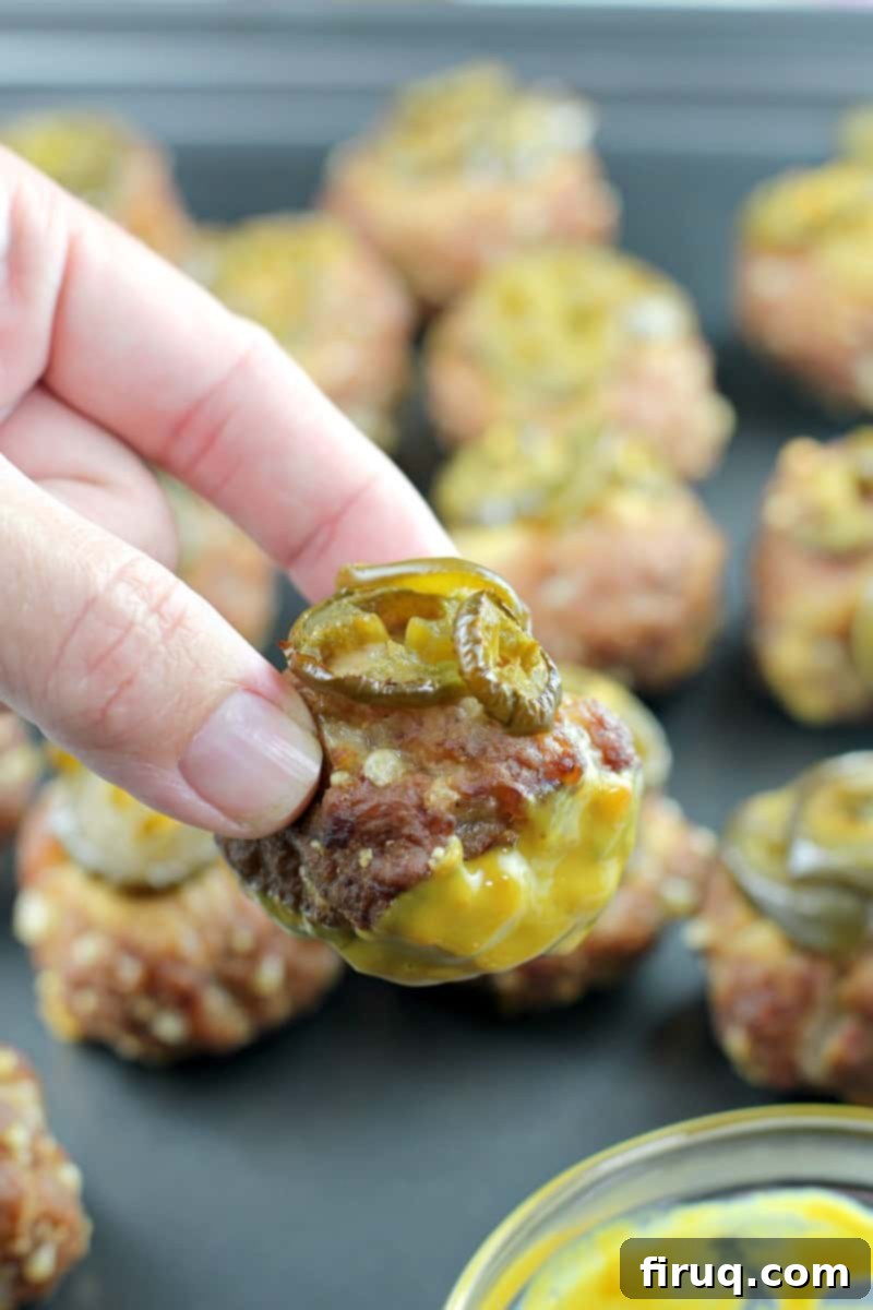 Smoky Sausage Bites 3 hand holding a smoked sausage ball dipped in honey mustard