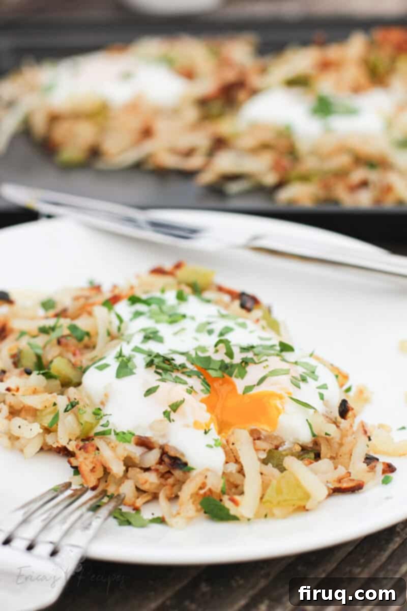 Sizzling Griddle Hash 10 serving of griddle hash browns on white plate with egg broken and yolk running out onto potatoes; rest of potatoes on sheet in background