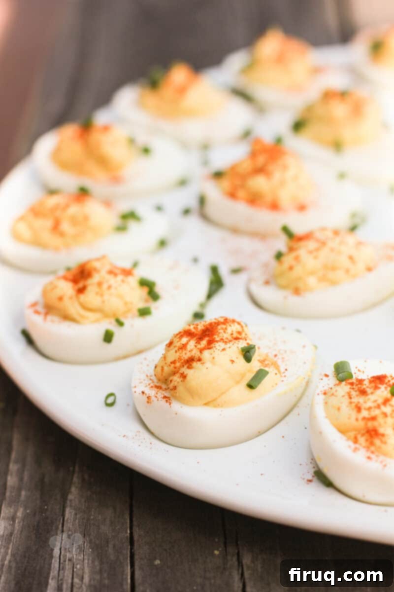 Zesty Stuffed Eggs 2 side view of perfectly piped deviled eggs topped with fresh chives on an elegant white serving platter