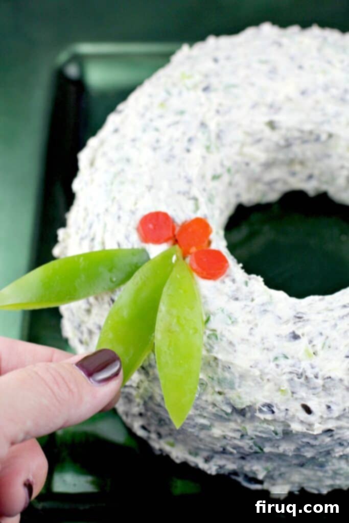 Festive Olive & Scallion Wreath Dip 13 A beautifully composed close-up of the Scallion Olive Party Dip Christmas wreath, adorned with intricately cut bell pepper holly leaves and berries, ready to be served.