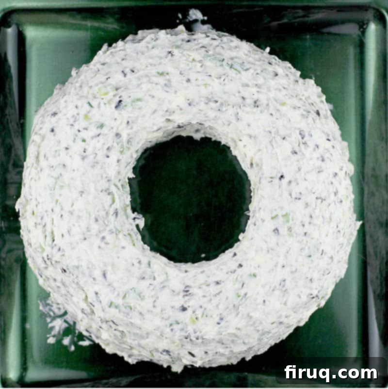 Festive Olive & Scallion Wreath Dip 9 A top-down view of the perfectly formed, un-garnished Christmas cheese wreath on a dark green serving plate, awaiting its festive decorations.