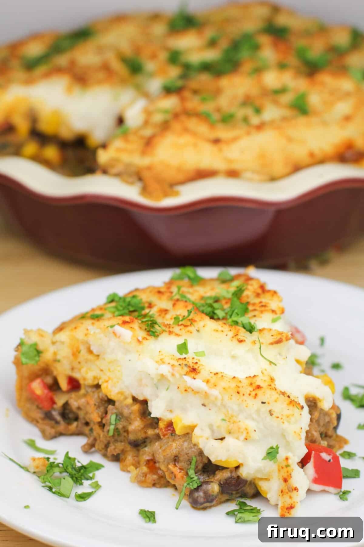 Ranchero Shepherds Pie 10 Serving of prepared Mexican shepherd's pie on a white plate with the red pie plate in the background
