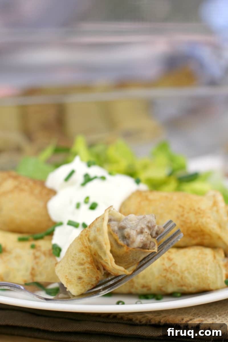 Gourmet Beef Stroganoff Crepes 3 a fork holding a bite-sized piece of filled crepe