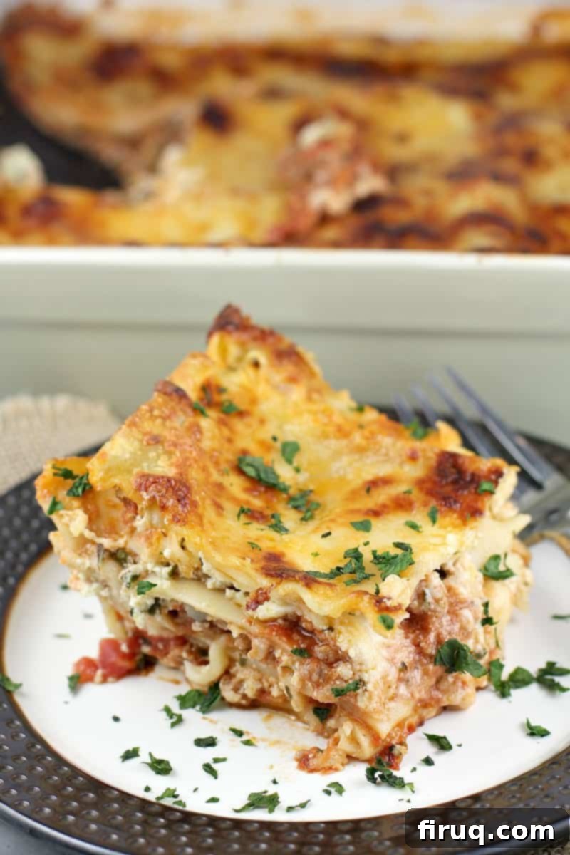 Classic Lasagna 13 plated lasagna on a brown rimmed plate with the ceramic lasagna dish in the background