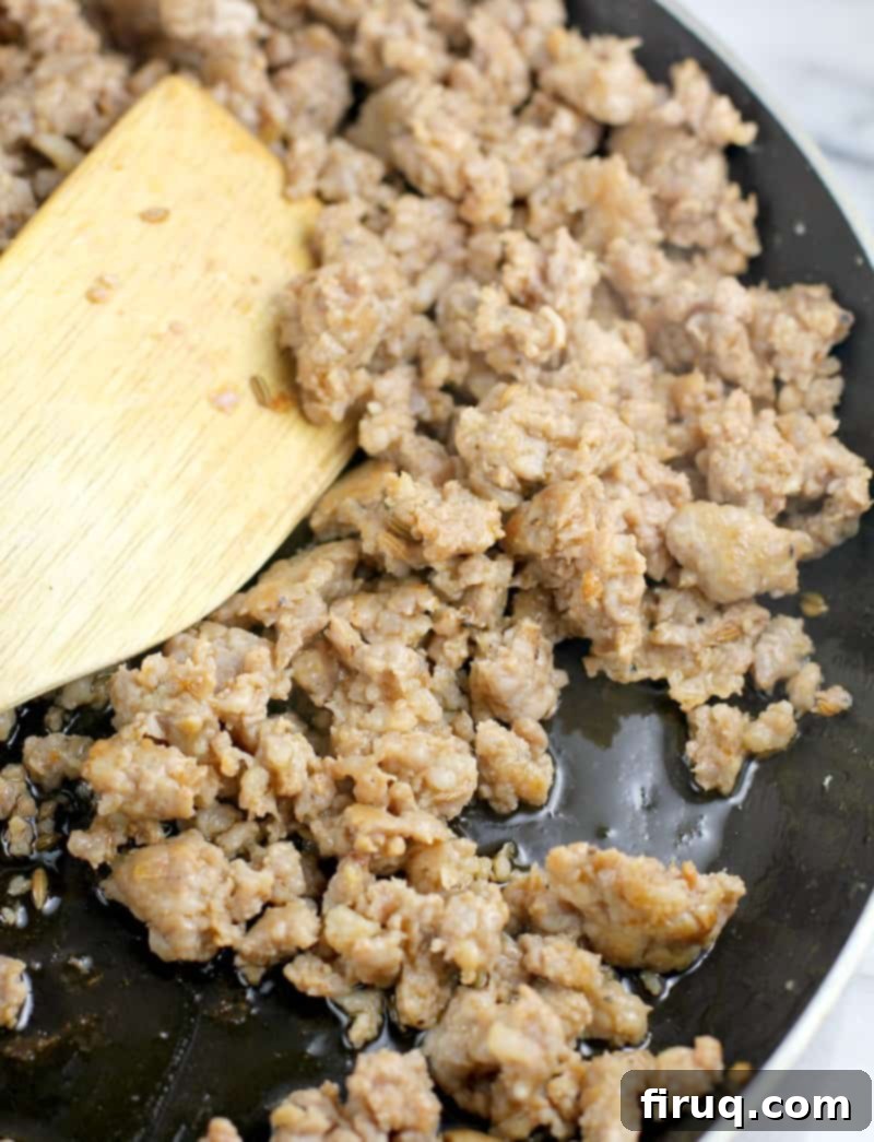 Classic Lasagna 5 juicy browned sausage (one of the ingredients for lasagna) in a skillet with a wooden spatula