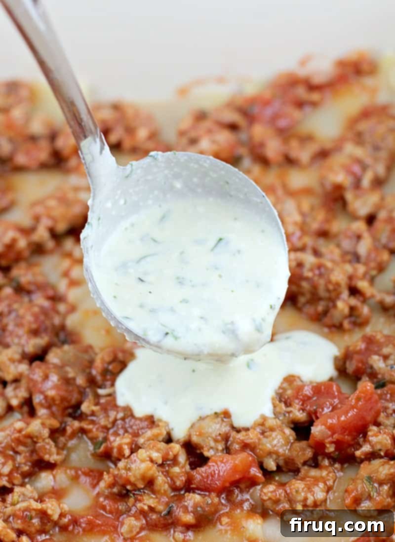 Classic Lasagna 7 white ricotta herb sauce being ladled on a layer of meat sauce