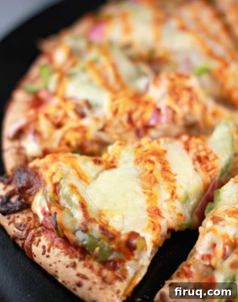 Spicy Buffalo Turkey Pizza 8 Top down/side angle from the left; the cooked buffalo turkey pizza on a black pizza stone surface, sliced into individual slices.