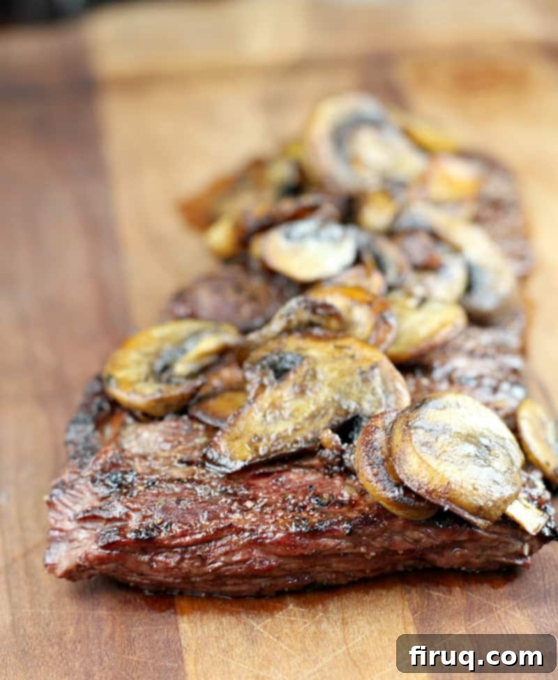 Bistro Garlic Butter Skirt Steak with Sautéed Mushrooms 4 garlic butter skirt steak topped with mushrooms on a wood board