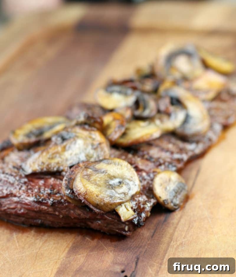 Bistro Garlic Butter Skirt Steak with Sautéed Mushrooms 6 side view of steak on board topped with mushrooms