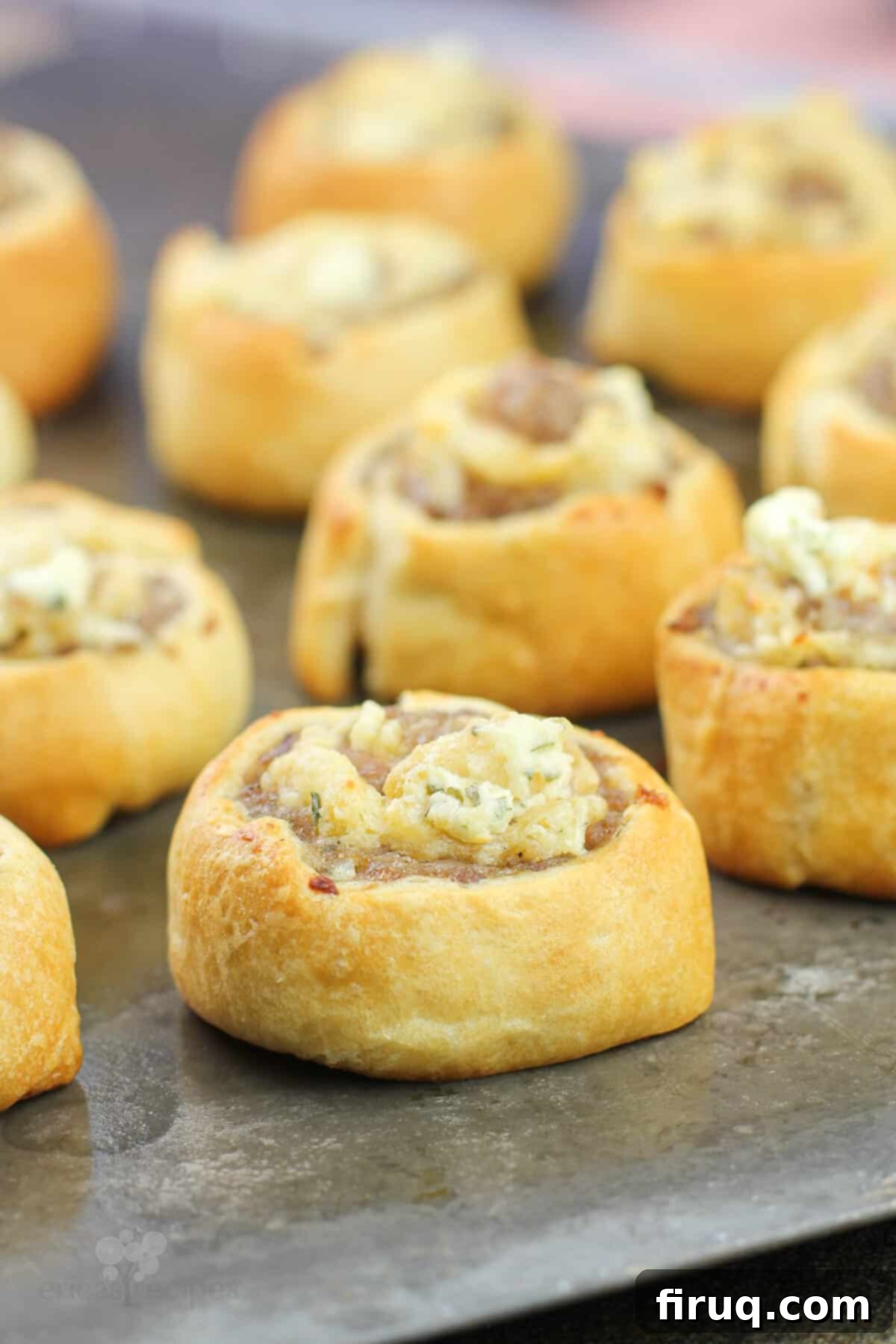 Creamy Boursin Sausage Swirls 7 Golden-brown, perfectly cooked Boursin and sausage pinwheels arranged on a baking sheet, fresh from the oven.
