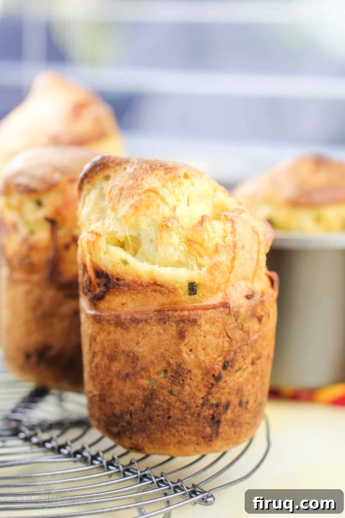 Poblano Cloud Bites 3 A single, perfectly browned popover with a crispy top on a wire cooling rack, showcasing its ideal texture and golden hue.