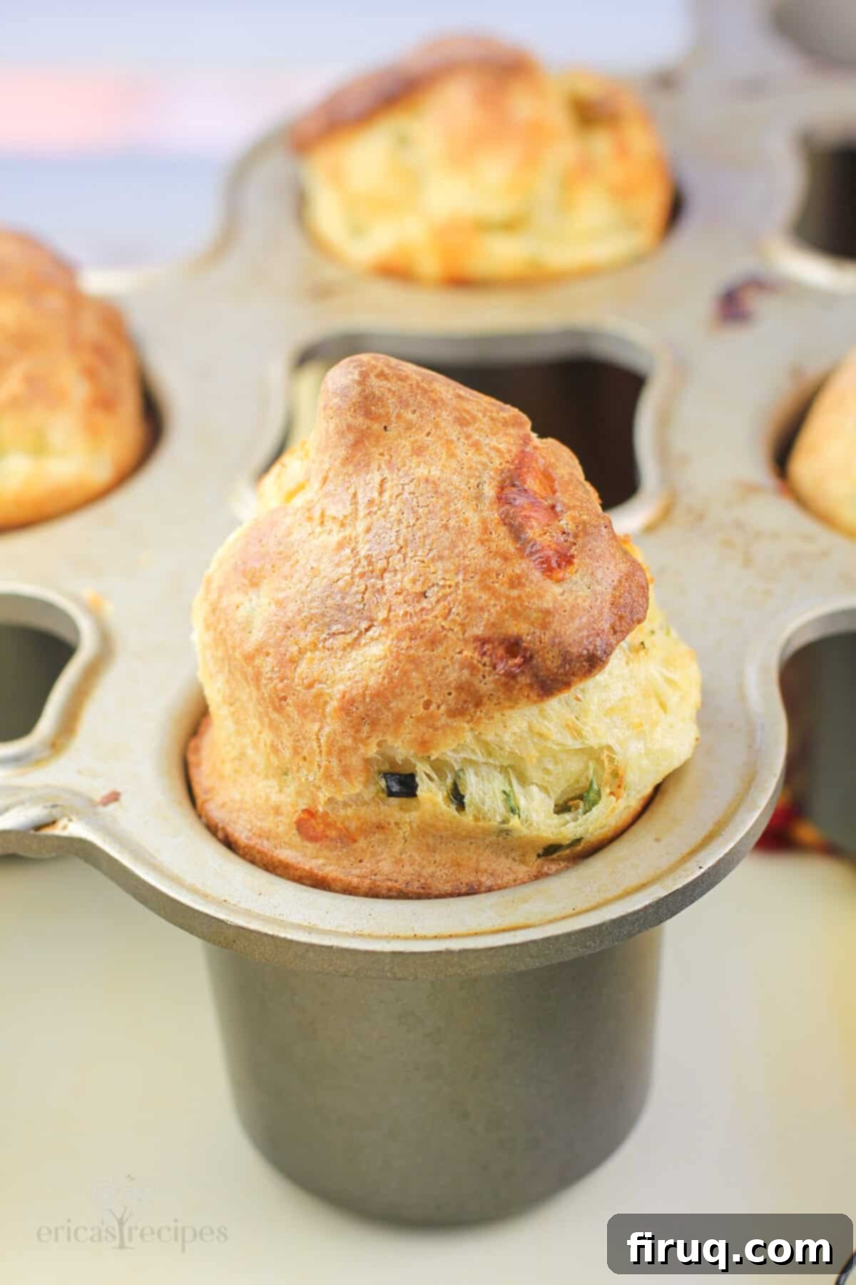 Poblano Cloud Bites 6 A close-up shot of a single, golden-brown popover still in its specific popover pan, showcasing its high rise and crispy edge.