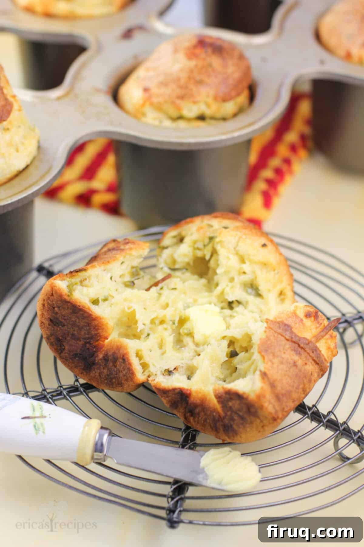 Poblano Cloud Bites 7 A close-up view of a perfectly split popover on a wire rack, with a small butter knife positioned to highlight its airy, hollow interior and flaky crust.
