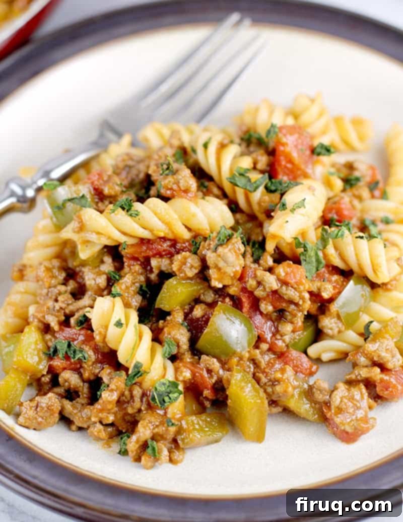 Homestyle Beef & Macaroni Bake 3 close in view of the sloppy joe dinner on a plate with a fork, highlighting the texture and rich sauce