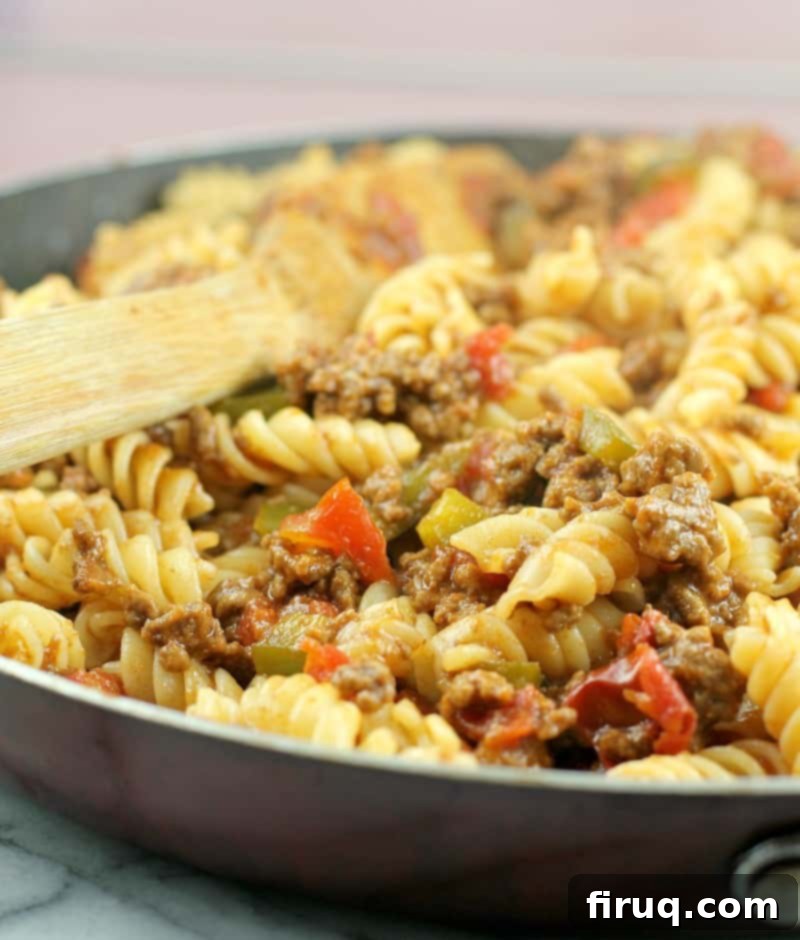 Homestyle Beef & Macaroni Bake 9 sloppy joe pasta in a skillet with a wooden spoon, ready to be served from the pan
