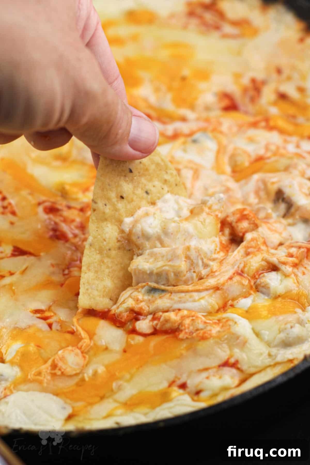 The Smokin' Buffalo Delight 2 hand holding a chip scooping up smoked buffalo chicken dip