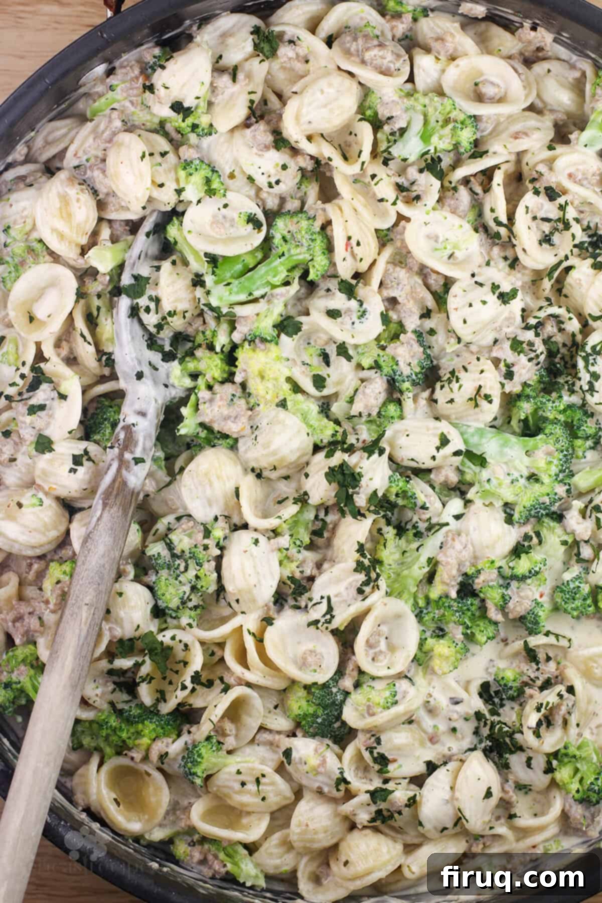 Sausage and Broccoli Orecchiette 3 Large skillet filled with creamy orecchiette pasta, broccoli, and sausage, with a wooden spoon for serving.