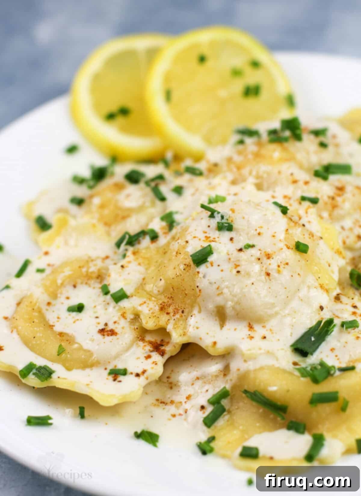 Bright Lemon Garlic Cream for Lobster Ravioli 2 prepared ravioli on white plate with lemon slices on the side