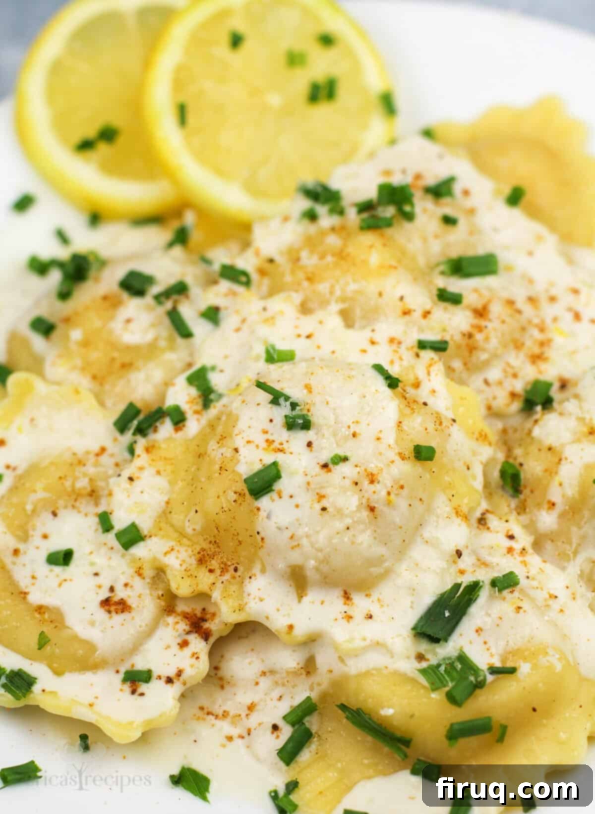 Bright Lemon Garlic Cream for Lobster Ravioli 3 prepared ravioli on white plate with lemon slices on the side