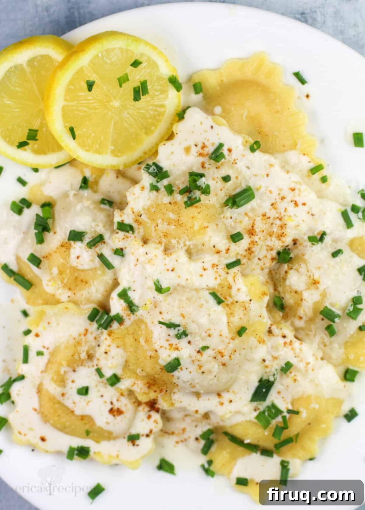 Bright Lemon Garlic Cream for Lobster Ravioli 5 prepared ravioli on white plate with lemon slices on the side