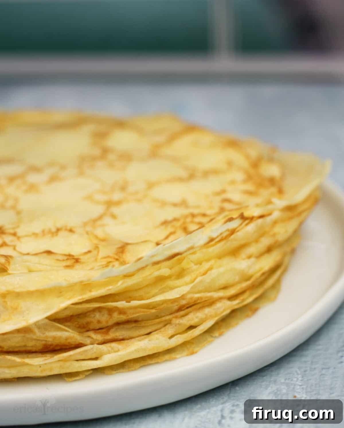 Zesty Lemon Crepes with Cloud Mascarpone 5 A neat stack of golden, freshly made lemon crepes on a white dish, ready for assembly
