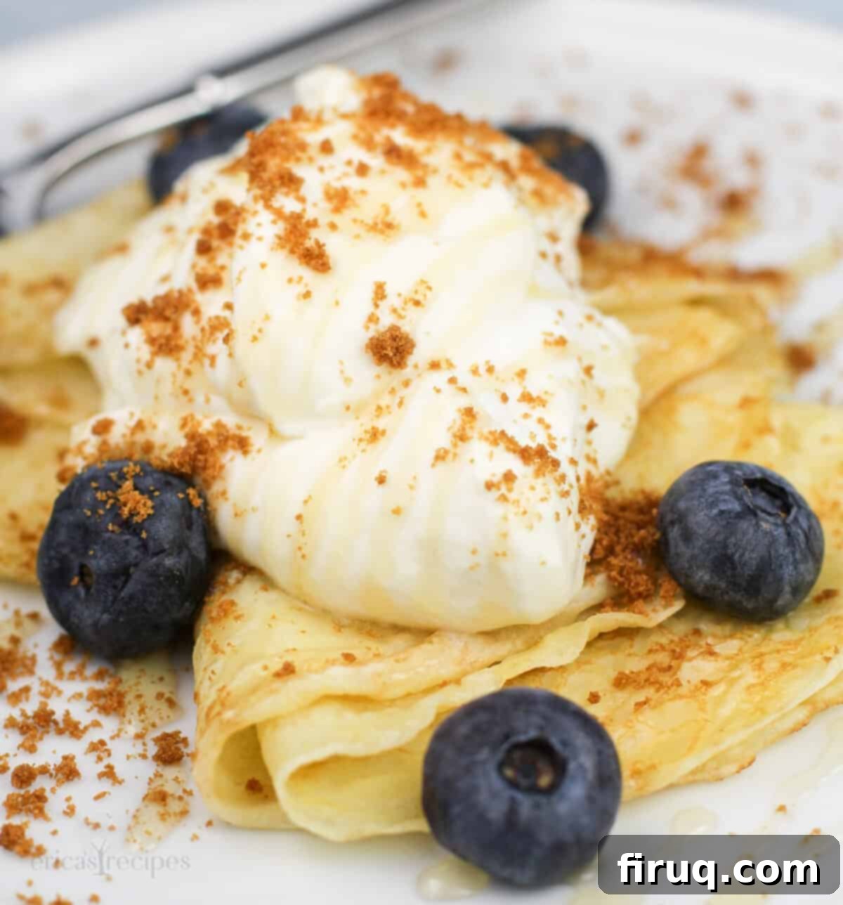 Zesty Lemon Crepes with Cloud Mascarpone 8 A beautifully presented serving of lemon crepes with creamy lemon mascarpone, fresh blueberries, and honey on a white dessert dish