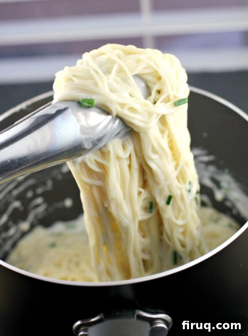 Velvety Sour Cream and Chive Pasta 13 thongs lifting up sour cream pasta from place saucepan