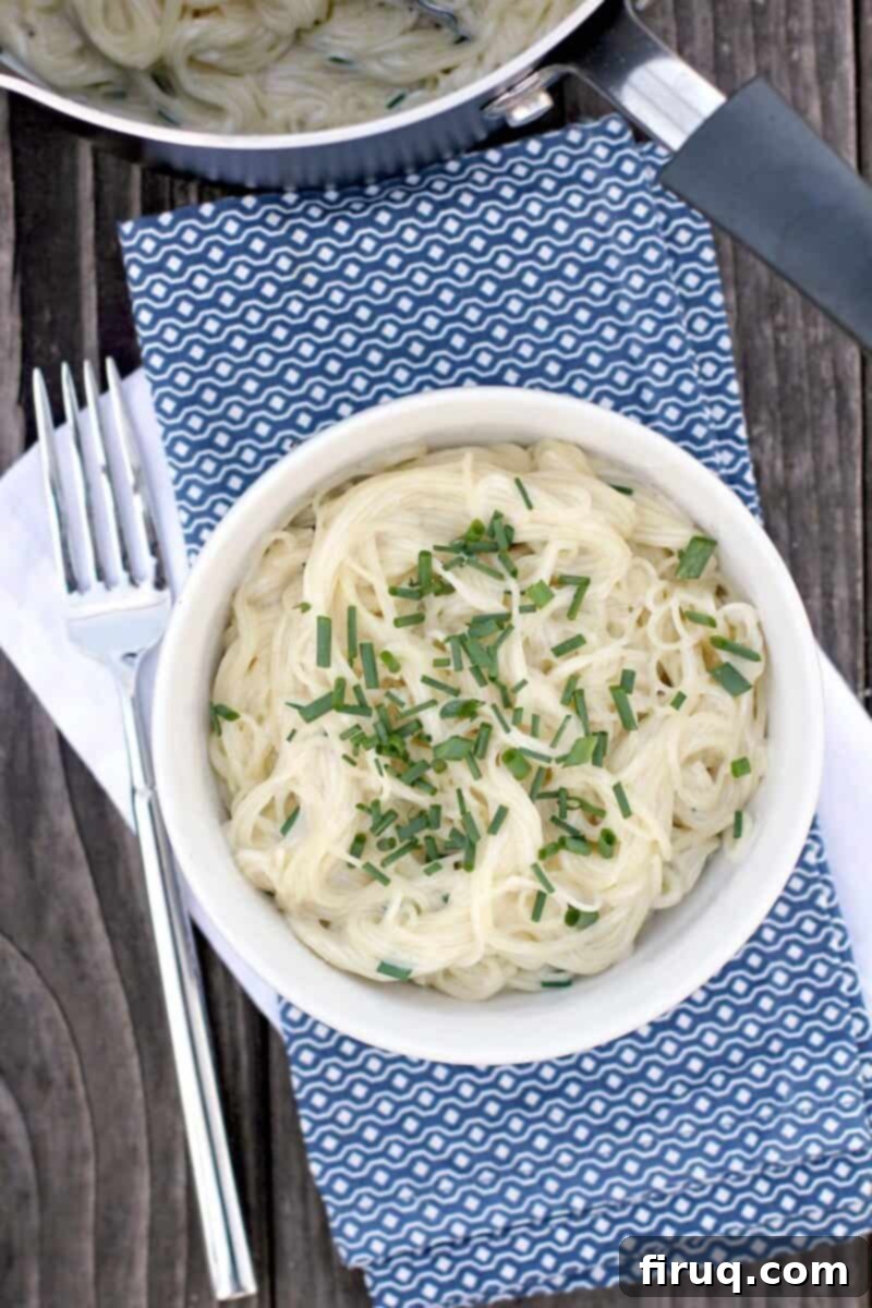 Velvety Sour Cream and Chive Pasta 14 top down view of pasta topped with chives in white bowl on blue napkin