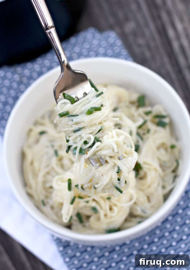 Velvety Sour Cream and Chive Pasta 4 fork lifting up sour cream pasta from bowl