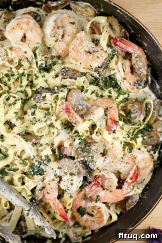 Velvety Sour Cream and Chive Pasta 6 top down view of the shrimp and pasta in a large skillet garnished with basil and parmesan, in a skillet with thongs in the corner