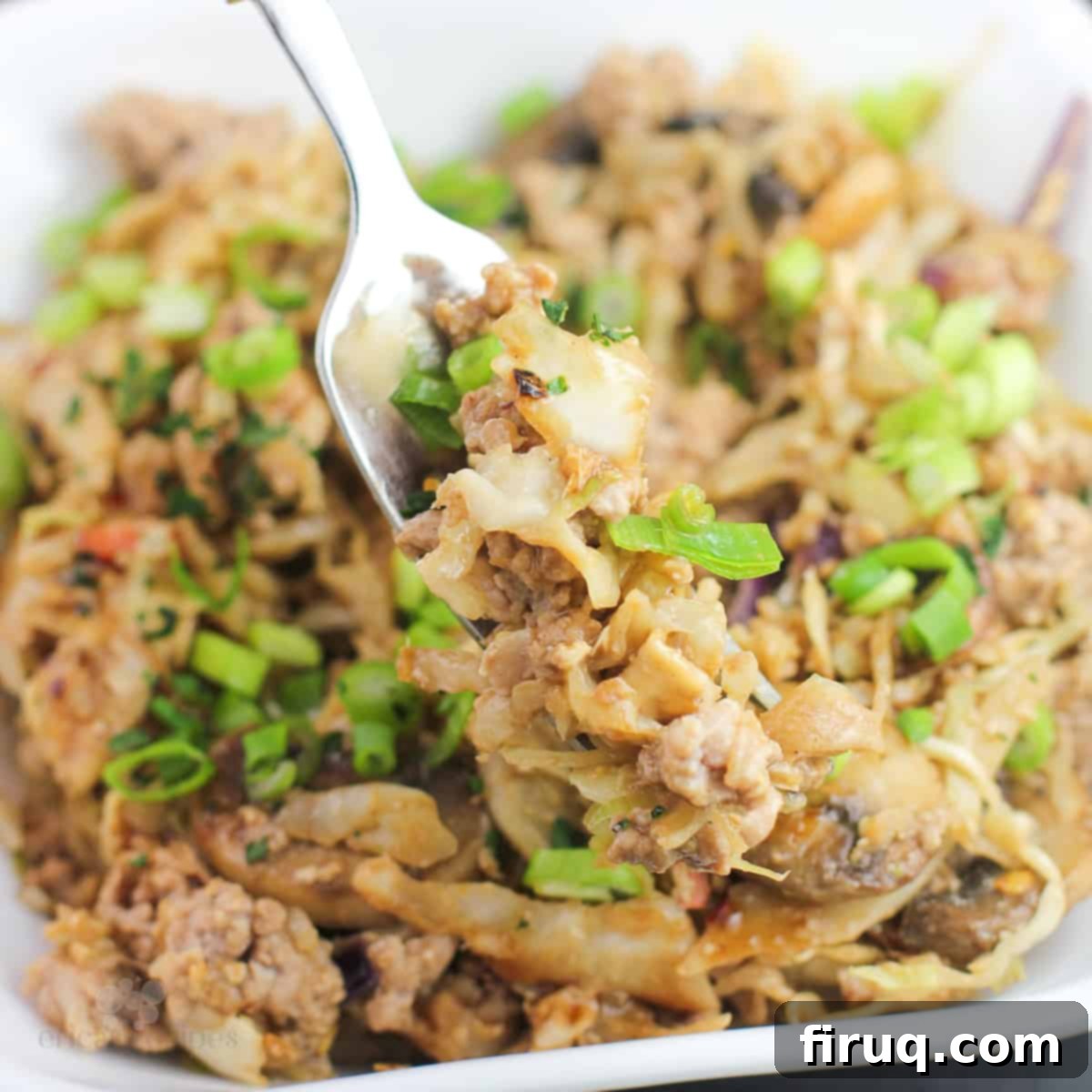 Blackstone Egg Roll Bowl 2 fork holding a bite-sized amount of egg roll in a bowl, showcasing the rich colors and textures of the dish