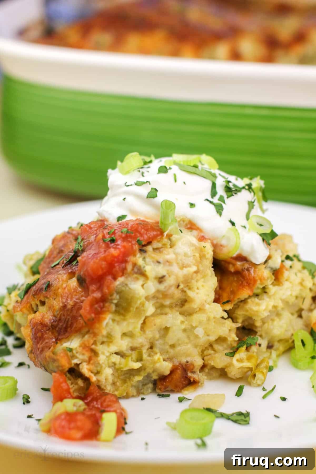 Zesty Green Chile Egg Delight 7 Serving of green chile egg bake on a white plate, garnished, with a green casserole dish in the background.
