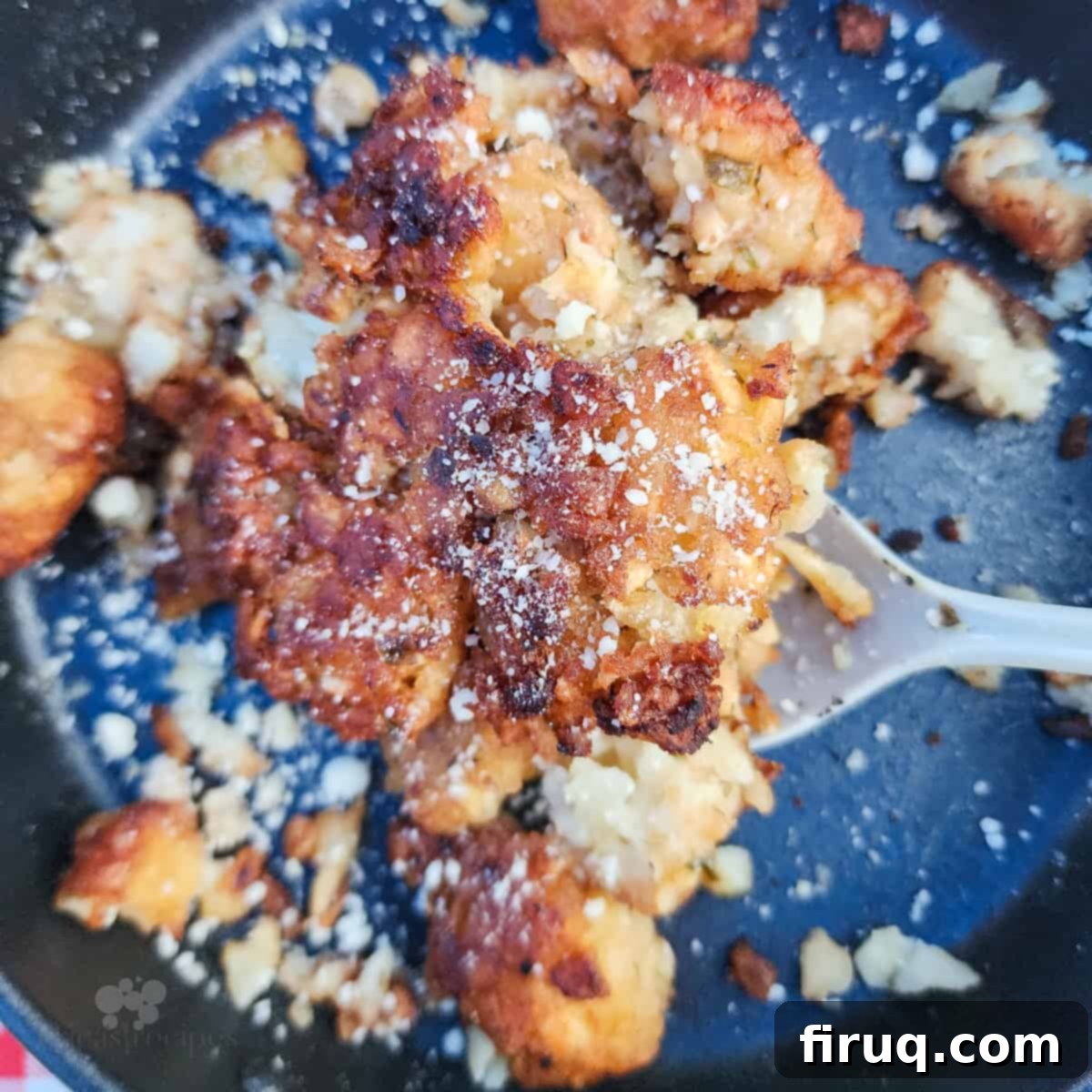 Golden Pie Iron Potato Pockets 2 cooked garlic parmesan tater tots on black surface with spoon