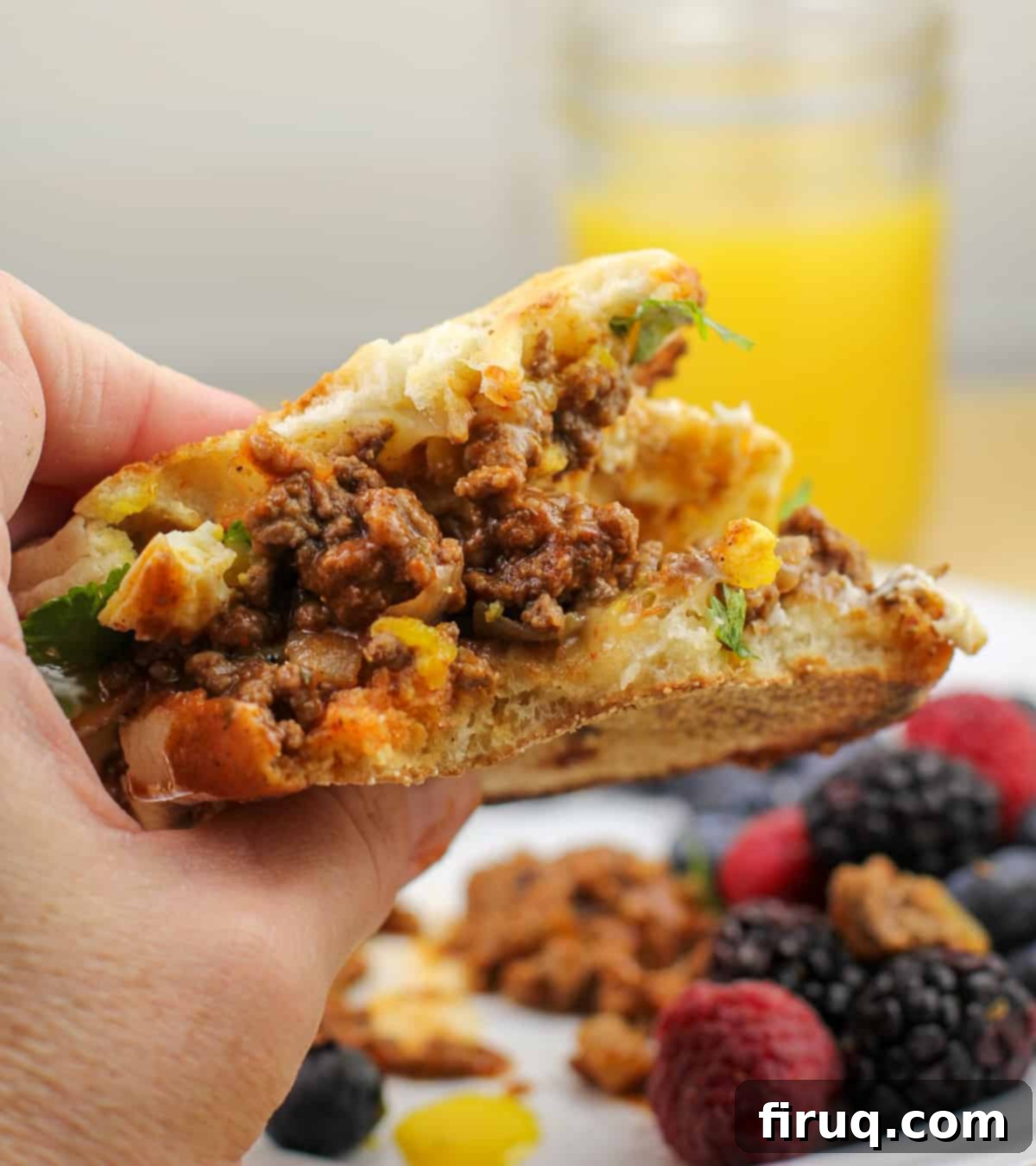 Taco Morning Stack 4 A hand holds a half-eaten, delicious taco breakfast sandwich, showcasing its layers of taco meat, egg, and cheese.