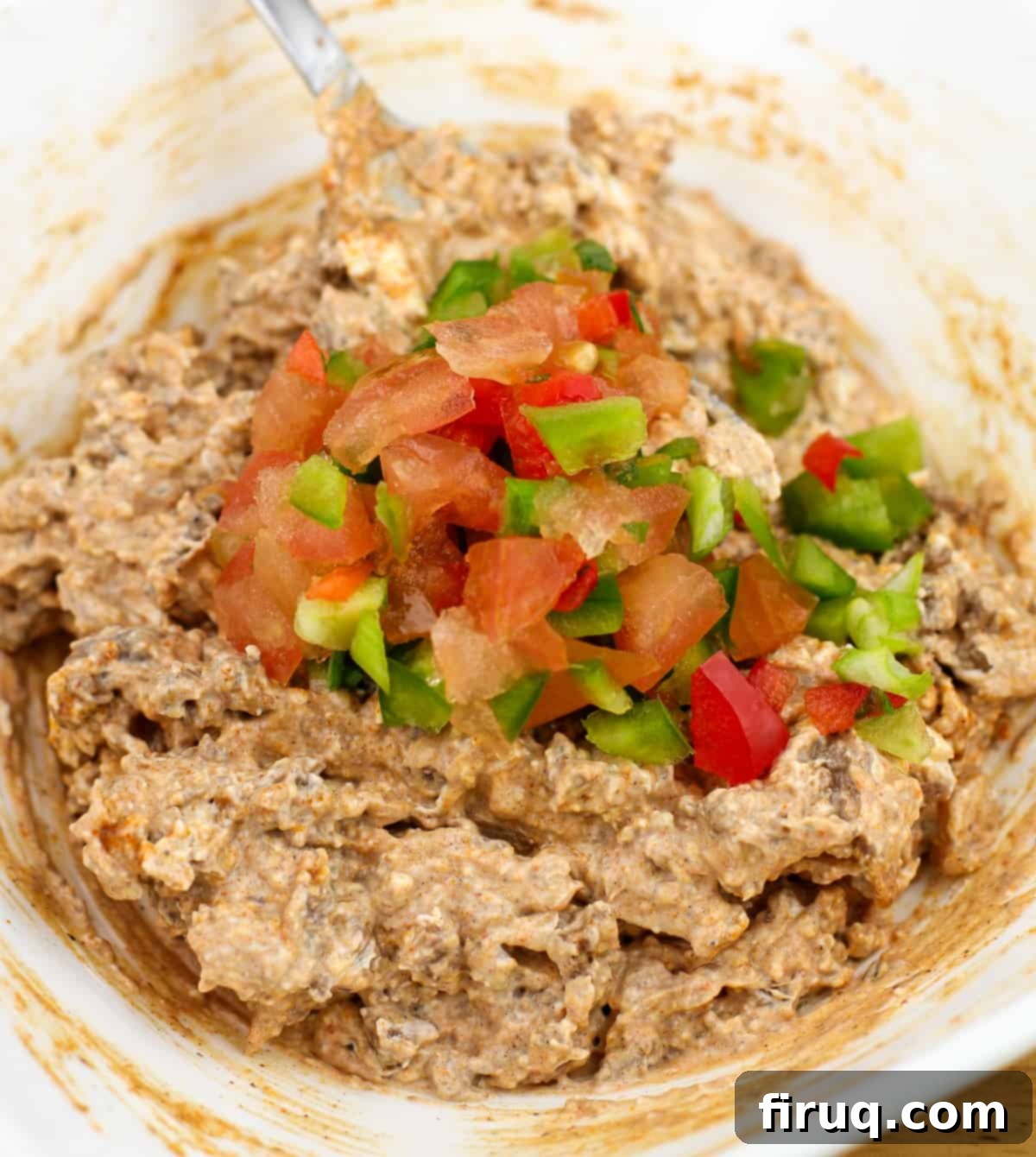 Tex-Mex Puff Pastry Spirals 3 Taco meat and cream cheese mixture in a white bowl, topped with colorful finely chopped red and green bell peppers and green onions, ready for assembly.