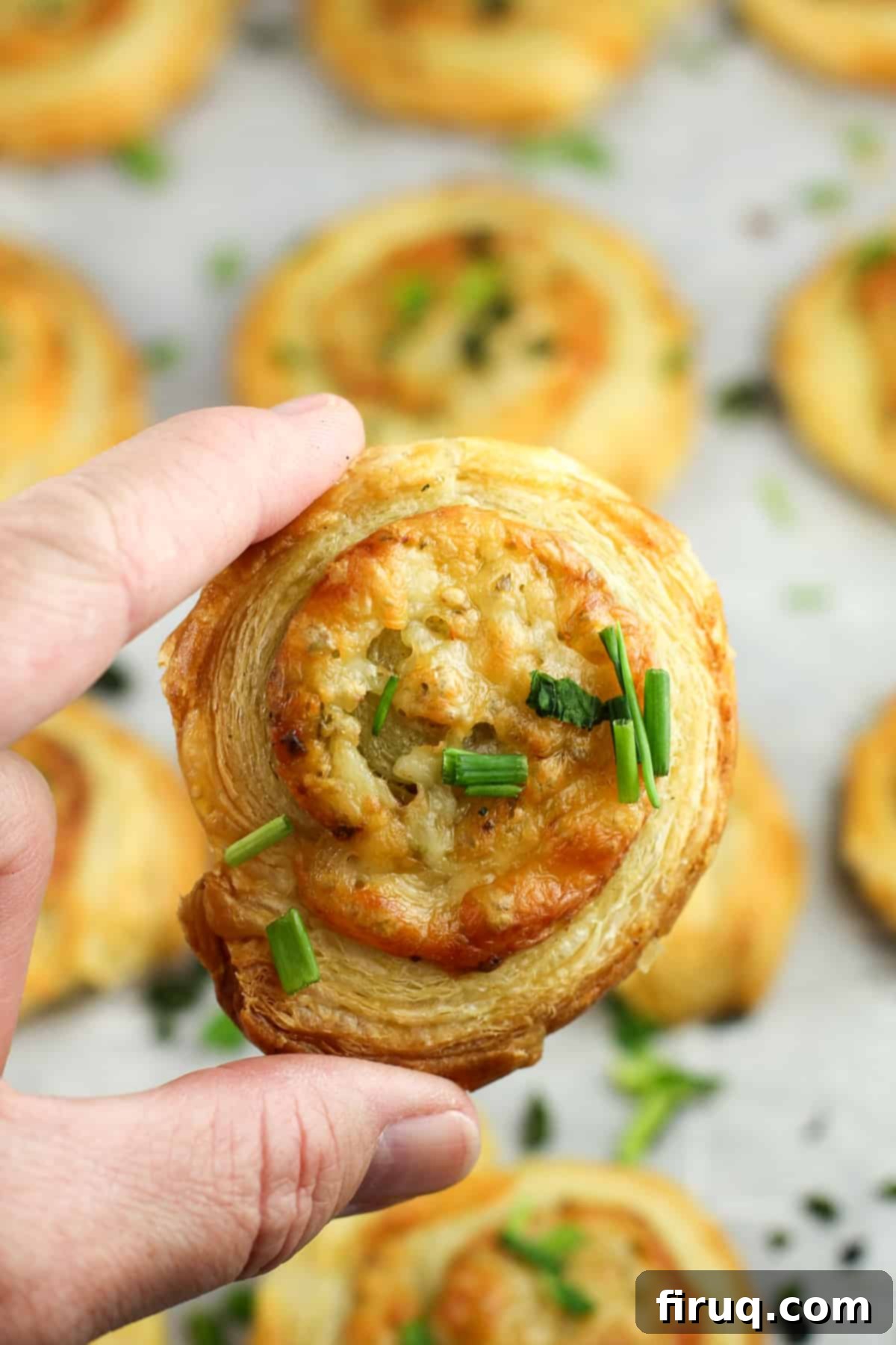 Savory Pesto Spirals 7 hand holding a cooked pastry pinwheel
